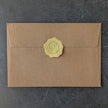 Brown handcrafted envelope with a exclusive golden wax seal on a dark gray background