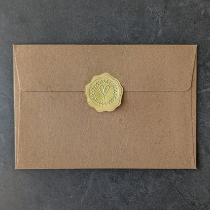Brown handcrafted envelope with a exclusive golden wax seal on a dark gray background